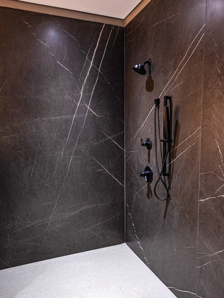 Shower with dark marble walls and matte black fixtures